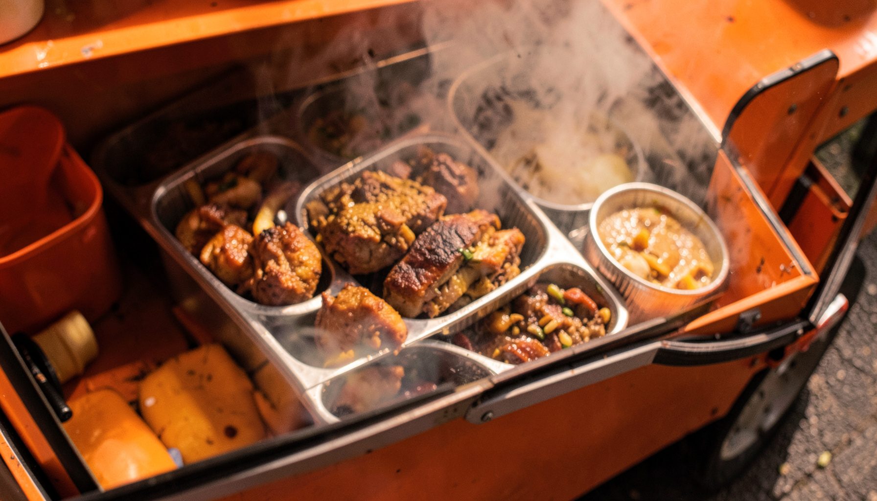Warm overhead view of a loaded food truck serving window with steam rising from freshly prepared dishes, rich browns and golden tones
