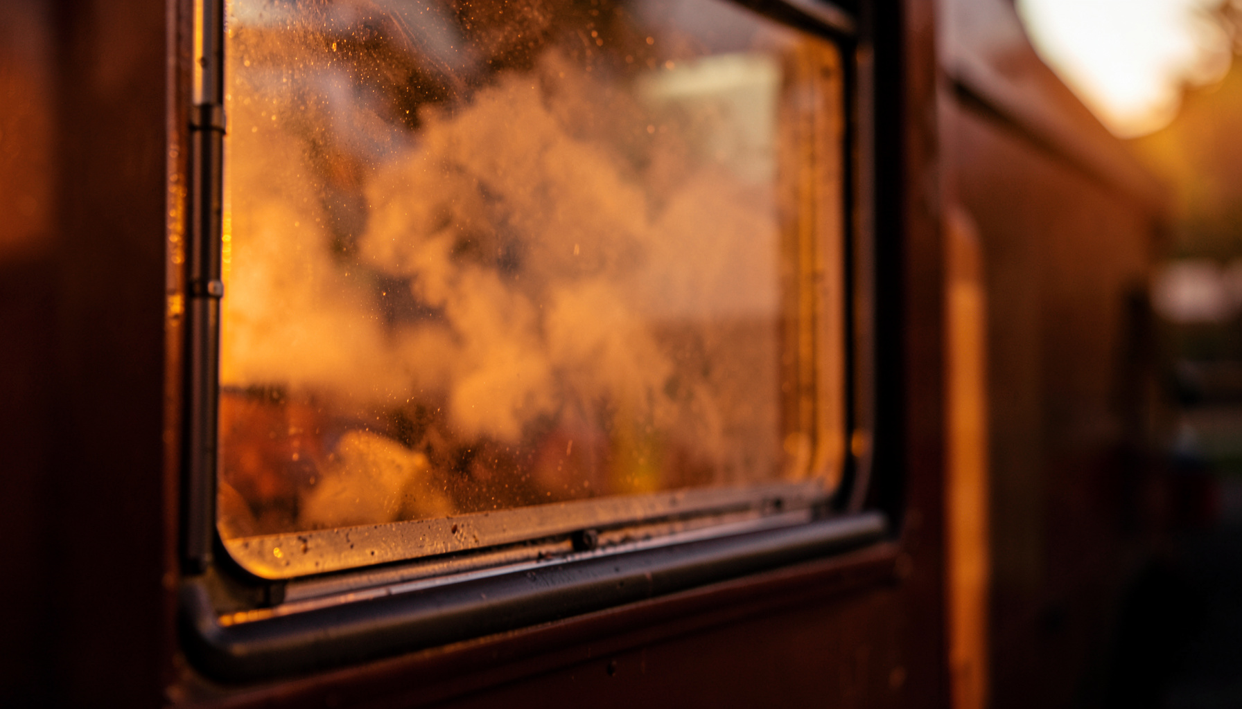 Warm evening light falling on a food truck window with steam rising, deep brown and amber tones